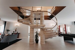 Un intérieur moderne avec un escalier en colimaçon, une table de billard et un coin salon.