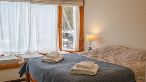 A hotel room with a bed, two rolled towels, a bedside lamp, and a window with curtains. - NOTRO 2 Tero (San Carlos de Bariloche)