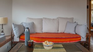 A sofa with pillows, a table with a bowl of snacks, a thermos, and a lamp. - NOTRO 2 Tero (San Carlos de Bariloche)