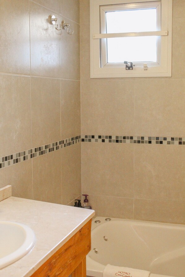 A bathroom with a bathtub, a window, and a tiled floor. - NOTRO 2 Tero (San Carlos de Bariloche)