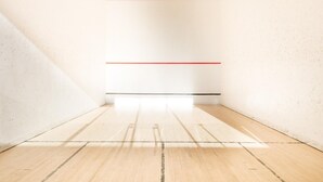 Una stanza con pavimento in legno, pareti bianche e linee rosse che delimitano lo spazio.
