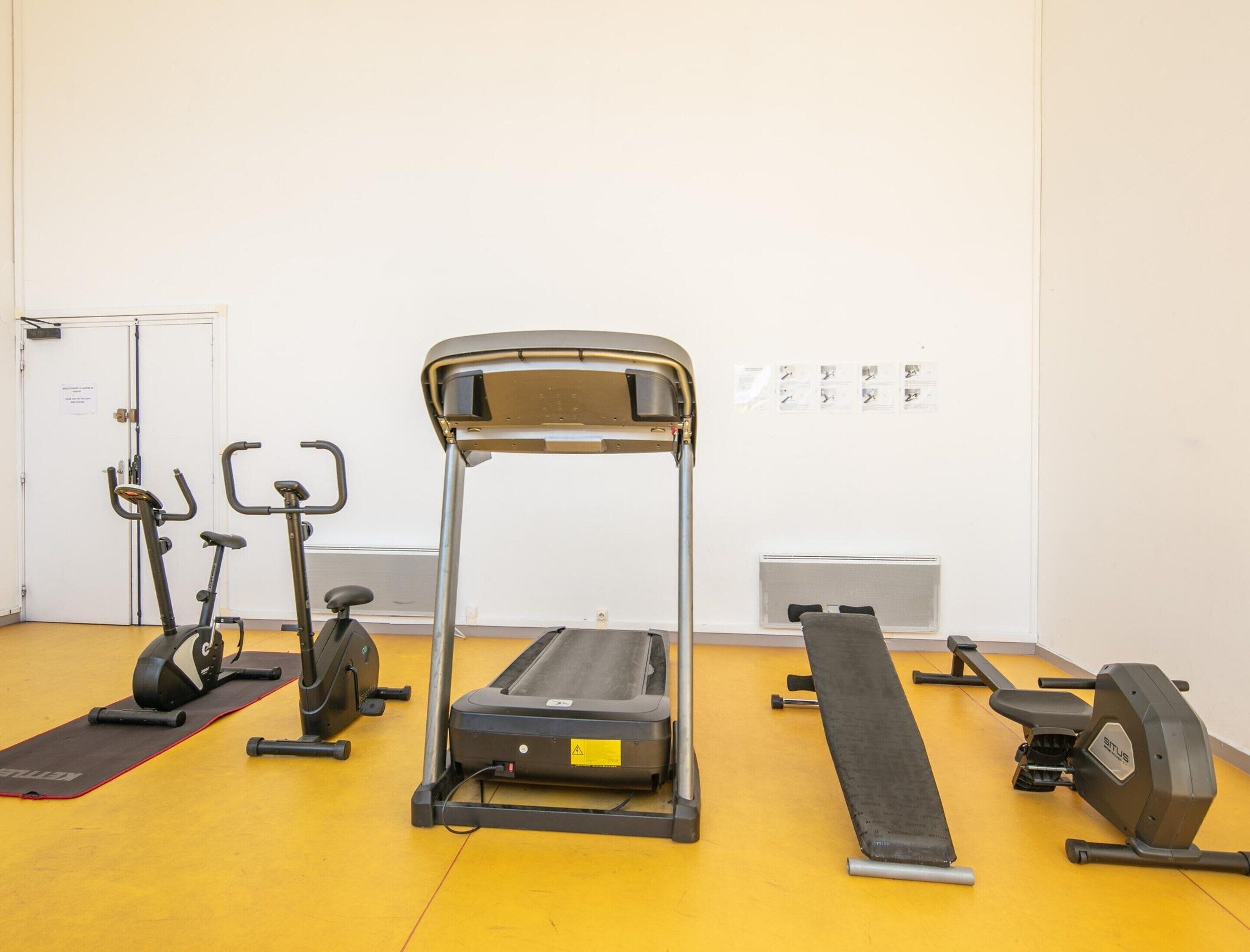 A gym with treadmills, elliptical machines, and a bench.