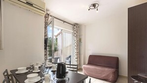 A dining area with a table set for two, a sofa, and a bar area. - Spacious Villa Stay for 6, Solenzara (Sari-Solenzara)