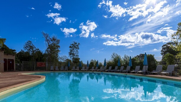 A clear blue pool with lounge chairs and umbrellas, surrounded by trees and a clear sky. - Spacious Villa Stay for 6, Solenzara (Sari-Solenzara)