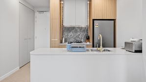Una cocina moderna con una isla central, horno empotrado y un refrigerador de acero inoxidable.