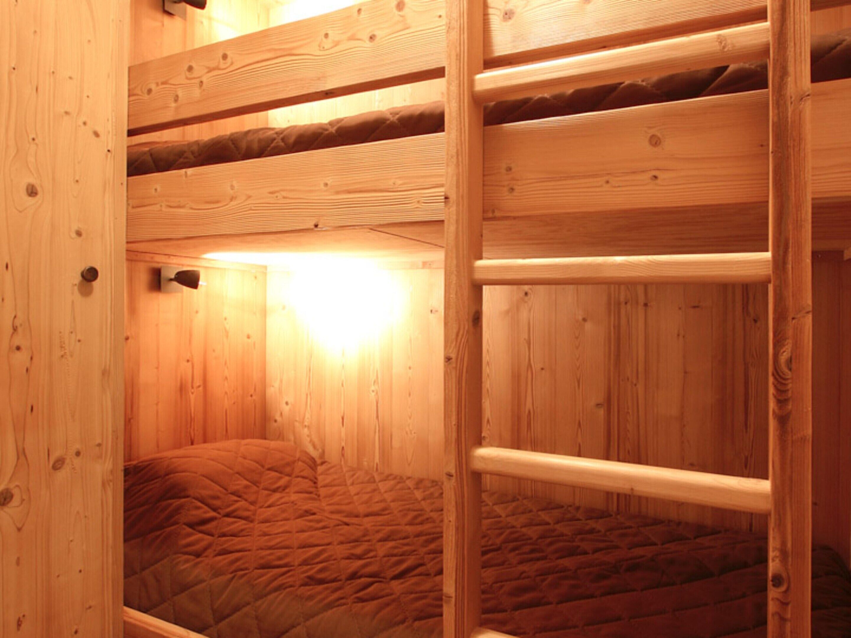 A wooden bunk bed with a quilted mattress.