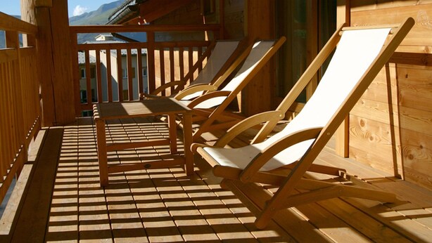 Une terrasse en bois avec des chaises longues et une vue sur les montagnes.