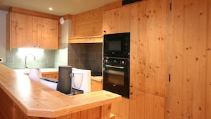 Une cuisine moderne avec des meubles en bois, un four à micro-ondes encastré et un four en acier inoxydable.