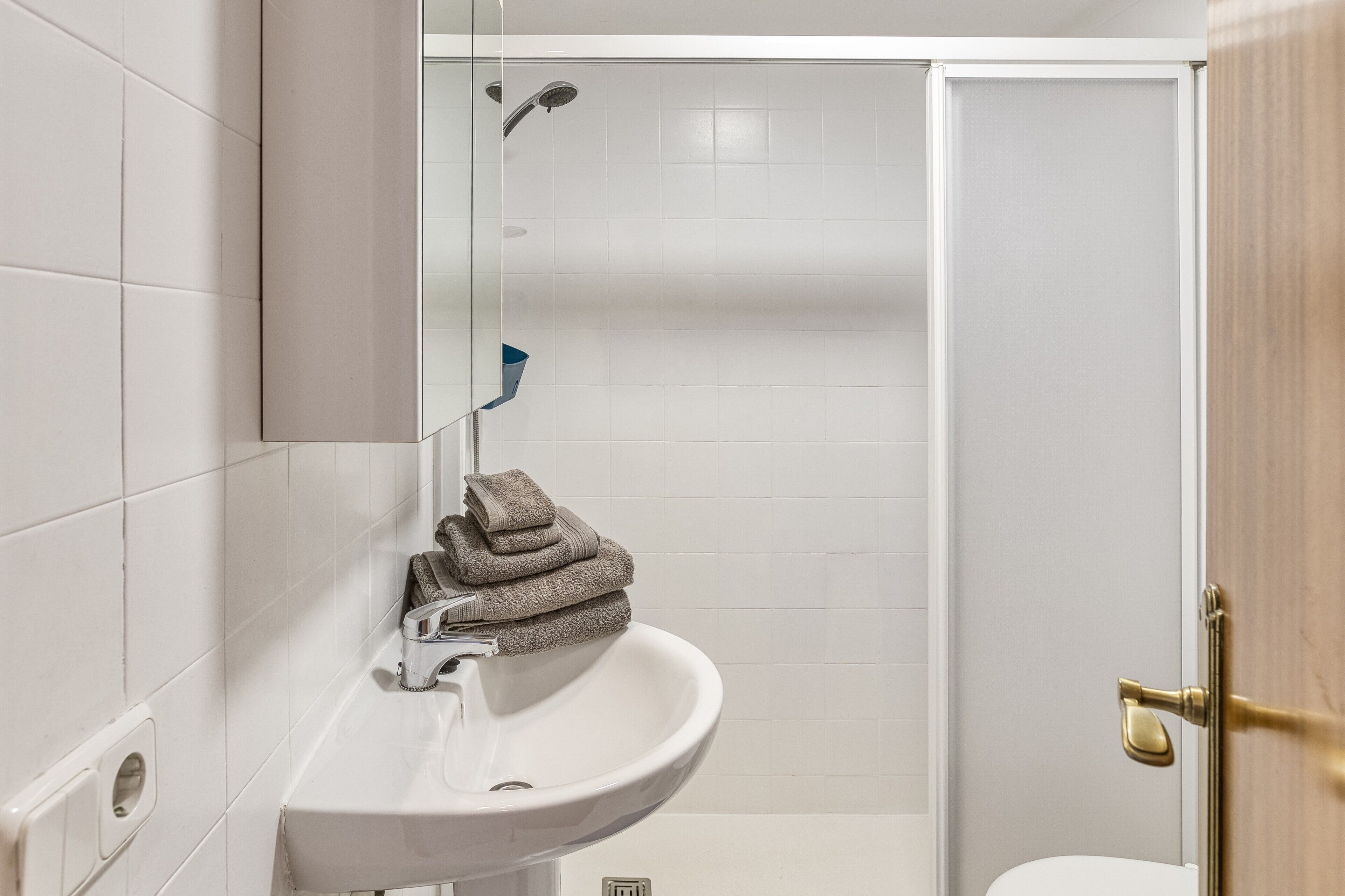 A bathroom with a white sink, a mirror, and a shower.