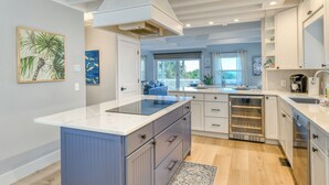 Una cucina moderna con isola centrale, mobili bianchi e vista sull'esterno.