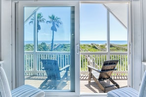 Ein Balkon mit Blick auf den Ozean, ein Holzstuhl und ein weißes Geländer.