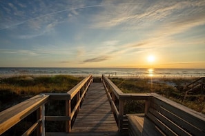 A wooden boardwalk leading to a beach with the sun setting in the background. - Seaside Siesta - Ocean Front, Private Beach Walkover, Charming (St. Augustine)