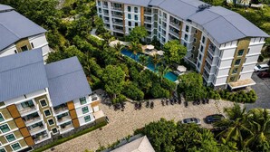 Un hotel a più piani con piscina immersa nel verde.
