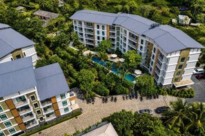 Een meerhoog hotel met een zwembad, omringd door weelderige begroeiing.