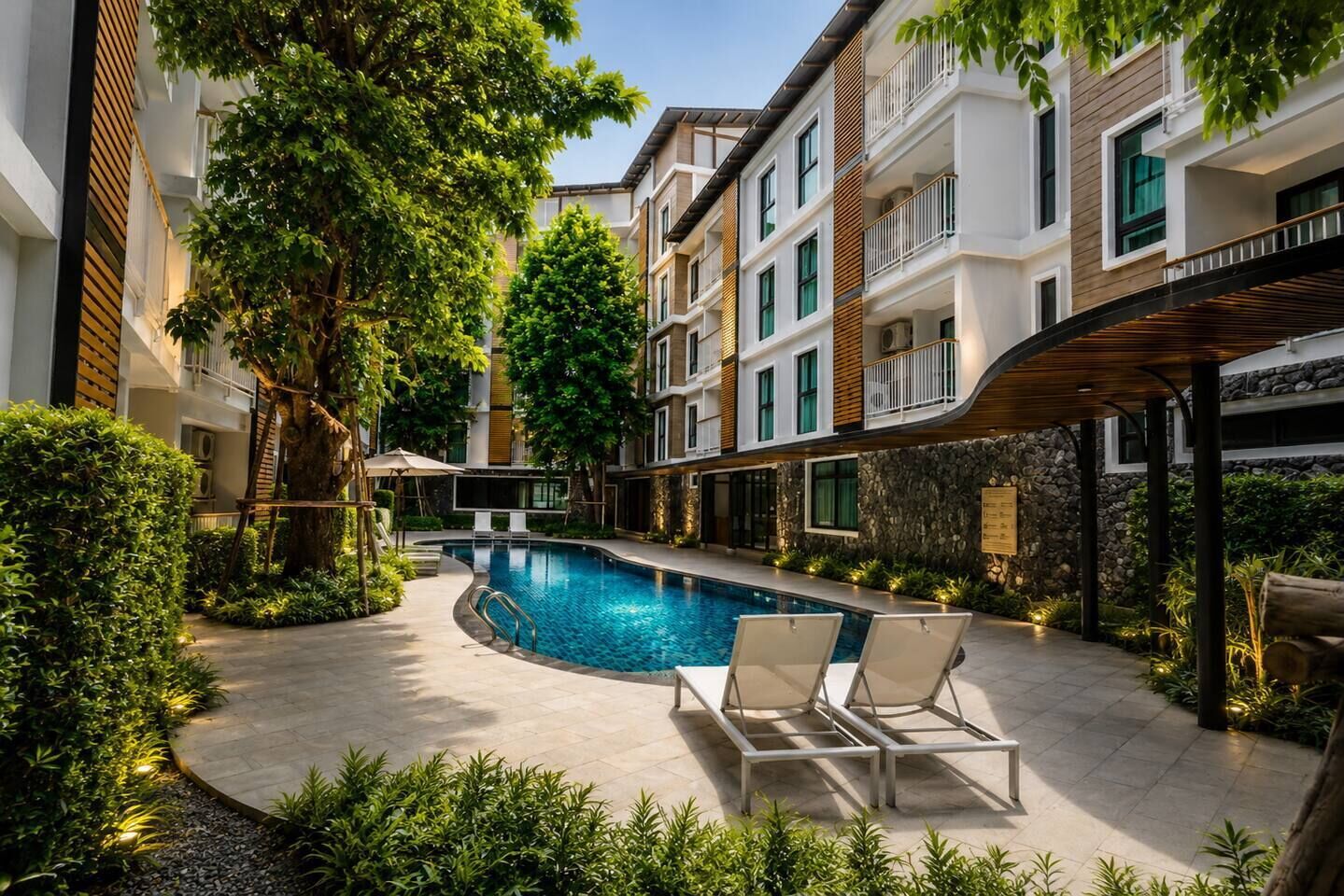 A modern hotel with a swimming pool, lounge chairs, and a covered patio area.