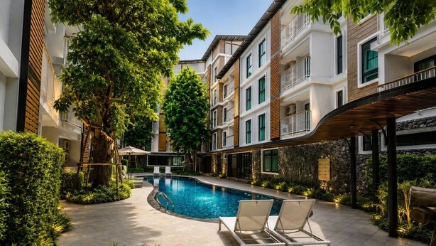 A modern hotel with a swimming pool, lounge chairs, and a covered patio area. - Stylish 1br Condo Rawai |walk to beach |pools&gym (Rawai)