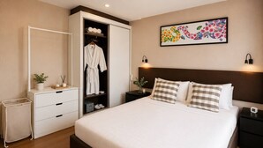 A hotel room with a bed, a wardrobe, a bedside table, a nightstand, and a wall-mounted artwork. - Stylish 1br Condo Rawai |walk to beach |pools&gym (Rawai)