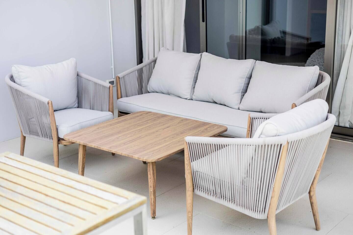 A modern outdoor seating area with a sofa, two chairs, and a wooden coffee table.