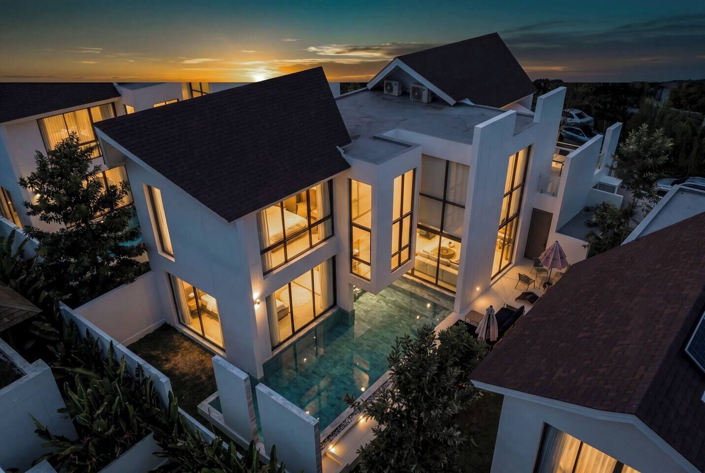 A modern multi-story house with a rooftop pool, large windows, and a well-maintained garden.