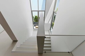 A modern interior with a staircase leading to a balcony with a view of greenery. - New Luxurious Villa 3 Br with private pool bangtao (Tambon Si Sunthon)