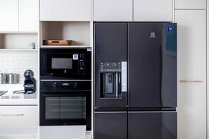 Una cocina con un refrigerador negro, un microondas y un horno.