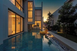 Un edificio moderno con piscina, mobiliario exterior y un gran ventanal.