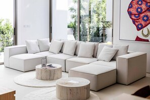 A modern living room with a sectional sofa and two round coffee tables. - New Luxurious Villa 3 Br with private pool bangtao (Tambon Si Sunthon)