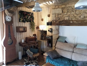 Une pièce rustique aux murs en bois, avec une radio ancienne, une horloge, un canapé et un tapis en peau de vache.