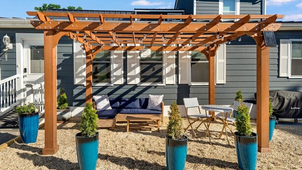A wooden pergola with a sofa and chairs underneath, surrounded by potted plants. - Petite Retreat at Harper's Ferry (Bolivar)