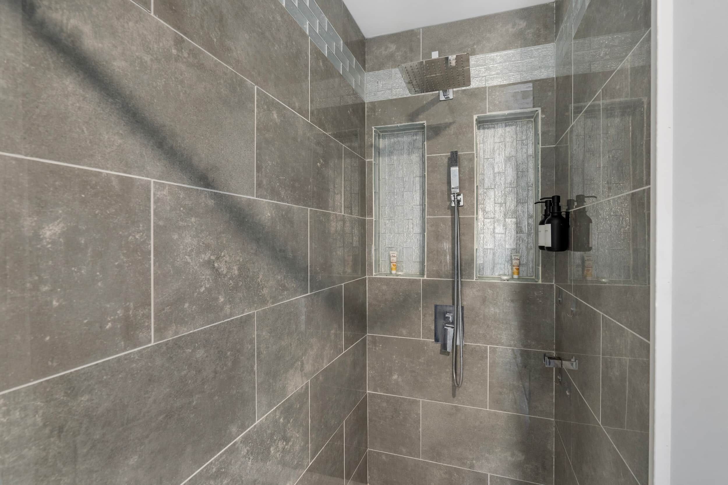 A shower with a handheld showerhead, a wall-mounted faucet, and a glass-enclosed shower area.