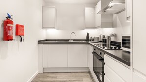 A modern kitchen with white cabinets, a stainless steel sink, and a built-in oven. - Bright & Spacious 1 Bedroom Apartment in Leeds (Leeds)