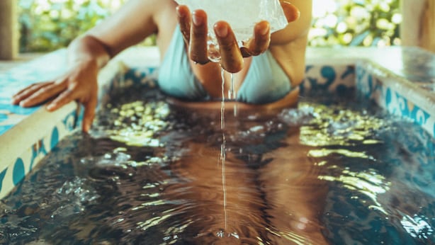 Una persona en un jacuzzi con techo de paja.