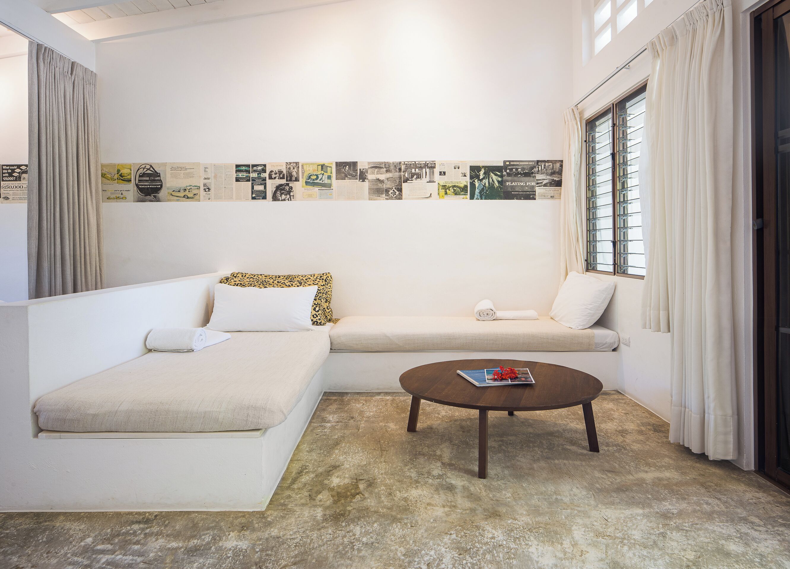 A modern living room with a sofa, a coffee table, and a wall decorated with various posters.