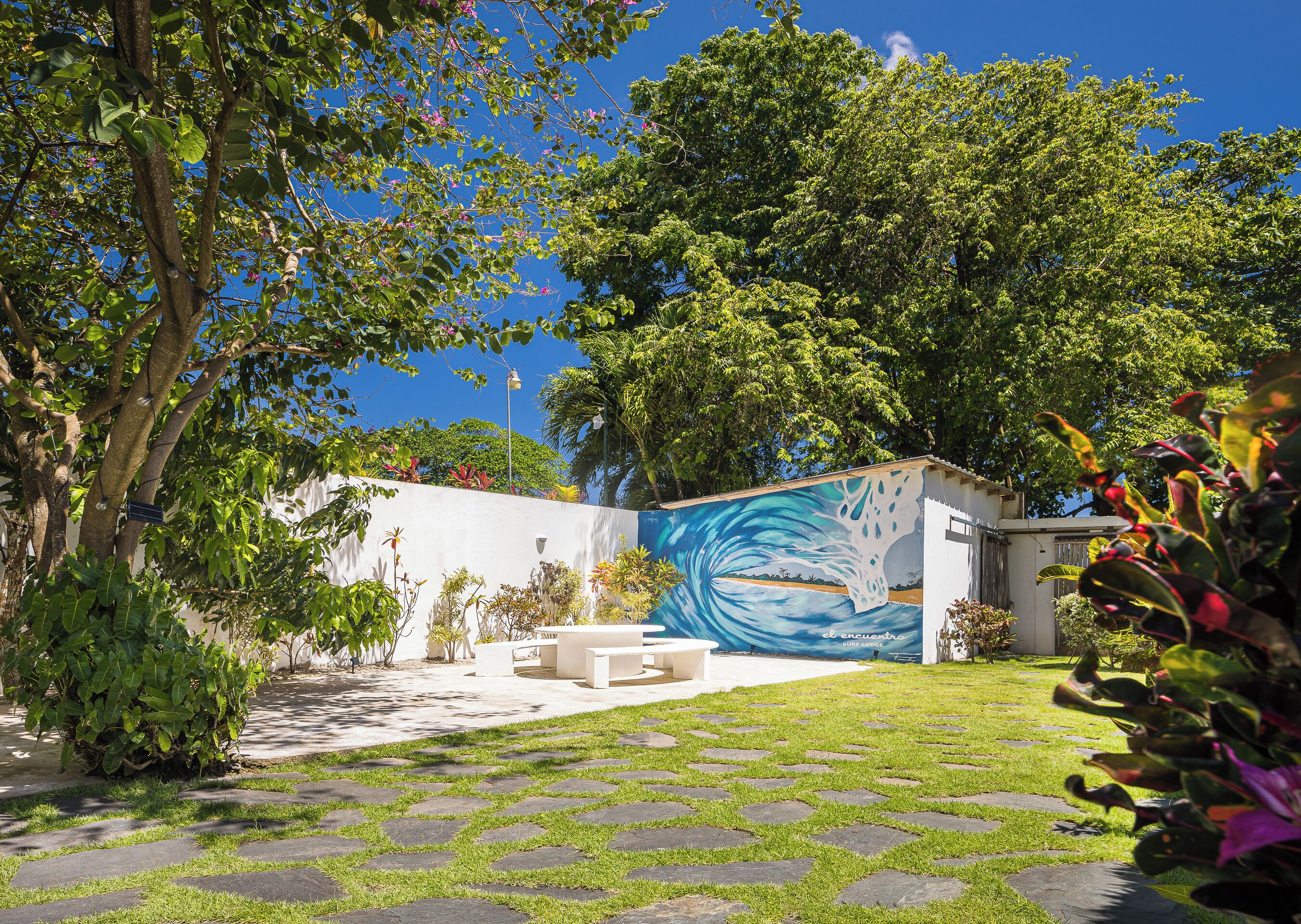 A courtyard with a mural, outdoor seating, and a white building.