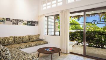 A living room with a sofa, a coffee table, a sliding glass door to a balcony, and a wall with framed pictures.