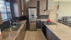 Eine moderne Küche mit einem Edelstahl-Kühlschrank, einem Gasherd und einem eingebauten Backofen.