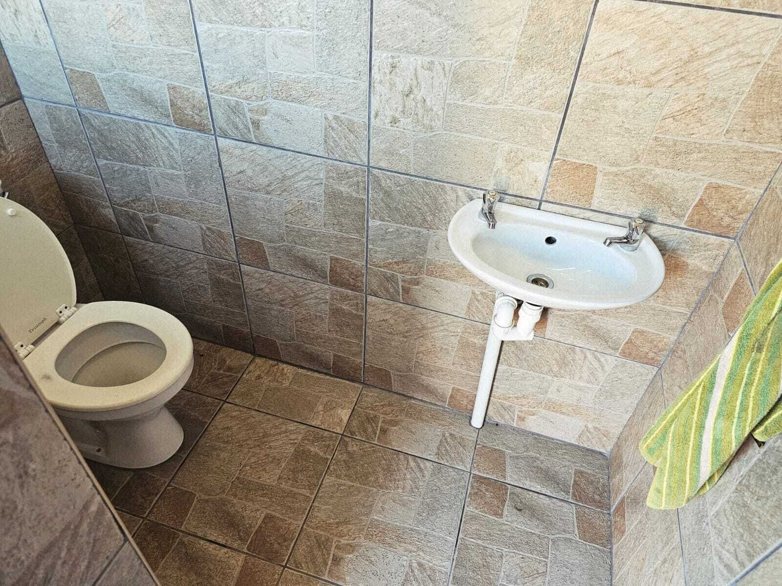 Une salle de bain avec des toilettes, un lavabo et des murs carrelés.