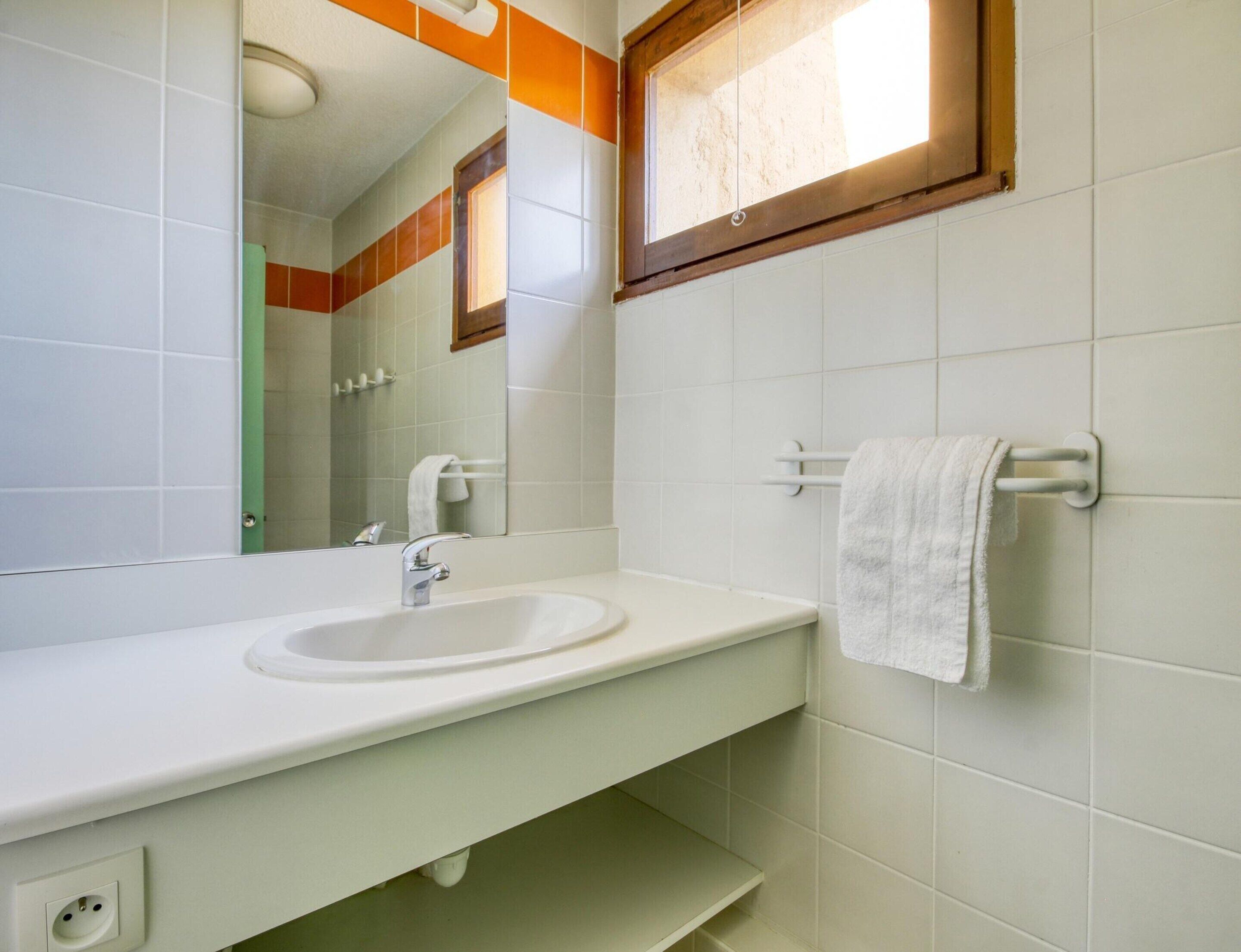 Une salle de bain avec un lavabo blanc, un miroir et un porte-serviettes.