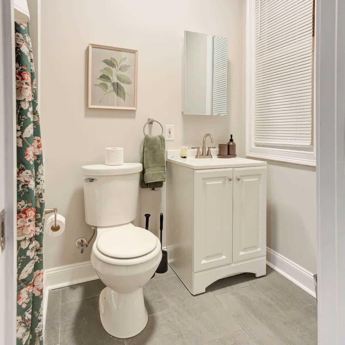A bathroom with a toilet, sink, and mirror.