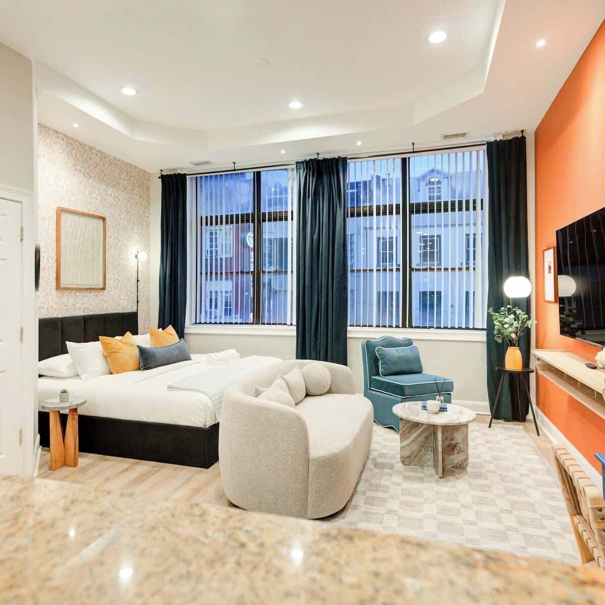 Ein modernes Hotelzimmer mit Bett, Sofa, einem kleinen Tisch und Fernseher.