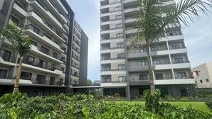 A modern multi-story building with balconies, a well-maintained garden area, and a clear sky. - Bantree Apartment by Cozy (Accra)