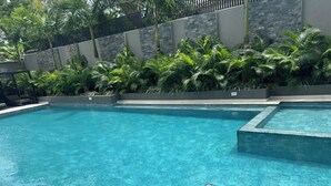 A clear blue pool with a stone wall and tropical plants. - Bantree Apartment by Cozy (Accra)