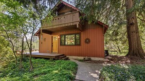 A wooden cabin with a balcony, a front door, and a small porch.