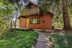 Une cabane en bois dotée d’un balcon, d’une porte d’entrée et d’un petit porche.