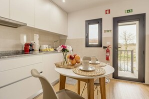 Eine moderne Küche mit Essbereich, einer Kaffeemaschine, einer Obstschale und einem Blumenvasen.