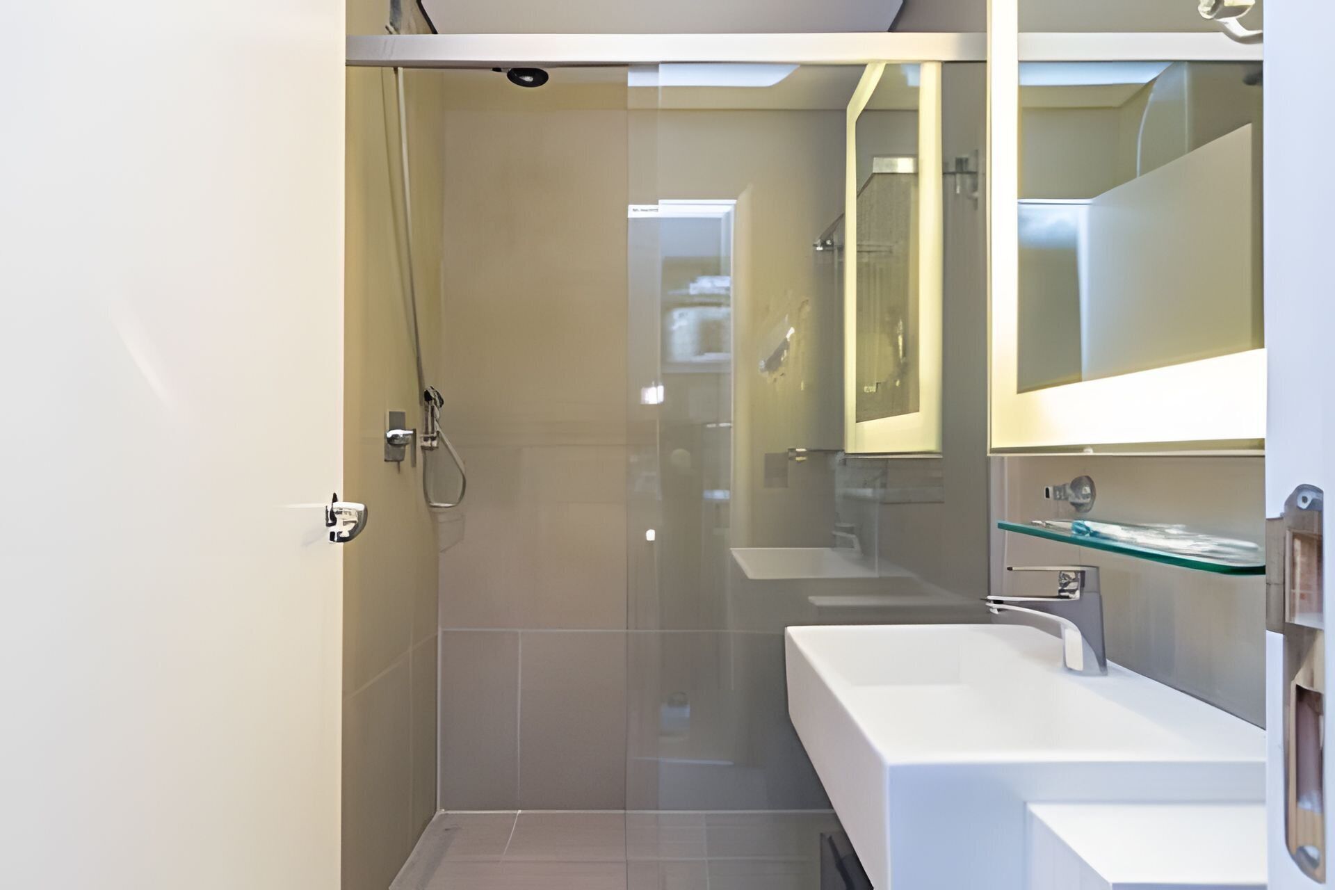 A modern bathroom with a glass shower enclosure, a white sink, and a mirror above the sink.