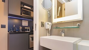 A modern bathroom with a white sink, a round mirror, and a hairdryer mounted on the wall. - Prime - Flats - Alpha Stay (Barueri)