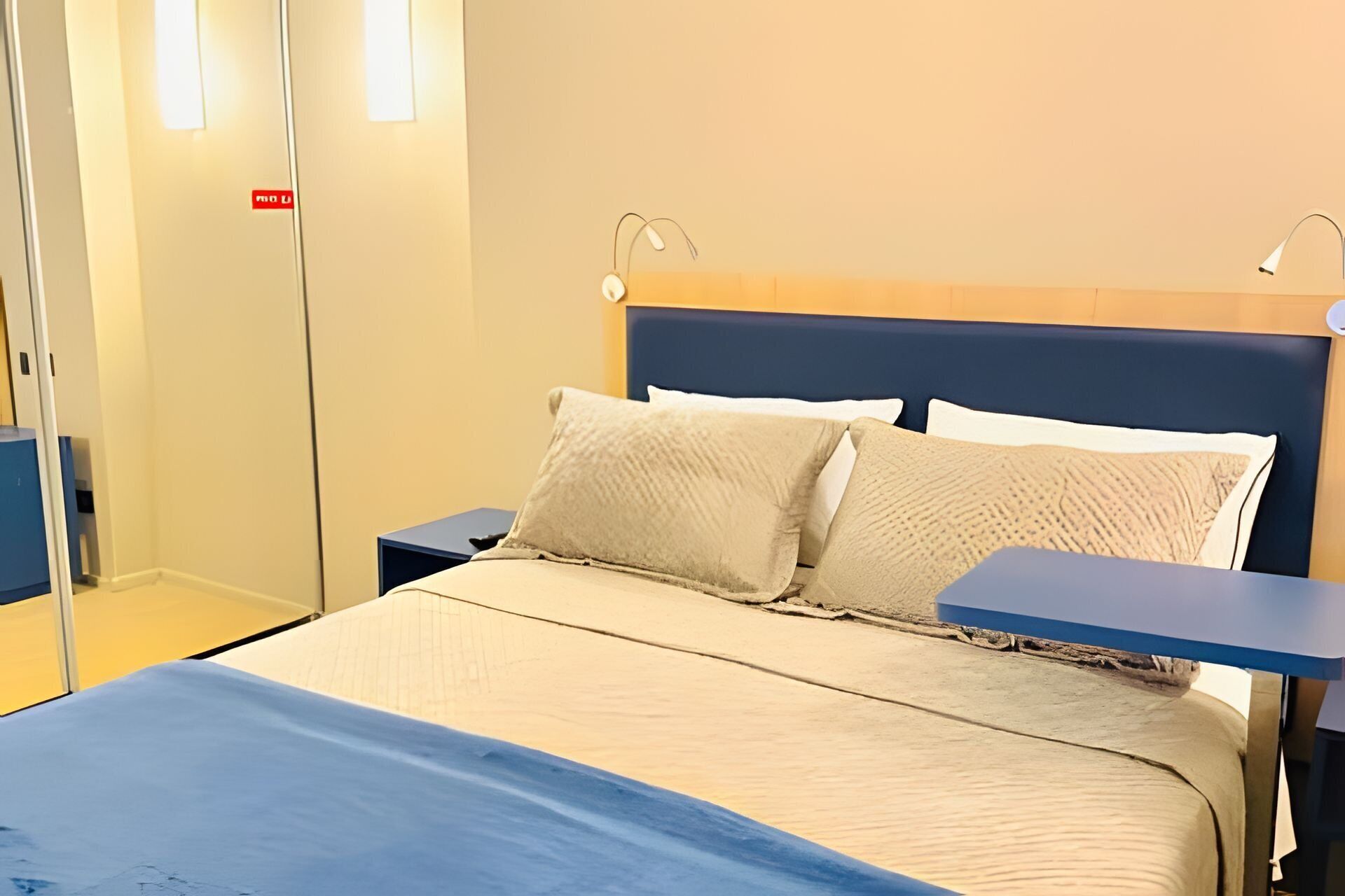 Une chambre d’hôtel avec un lit, des tables de chevet et une armoire.