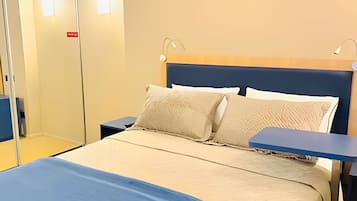 Une chambre d’hôtel avec un lit, des tables de chevet et une armoire.