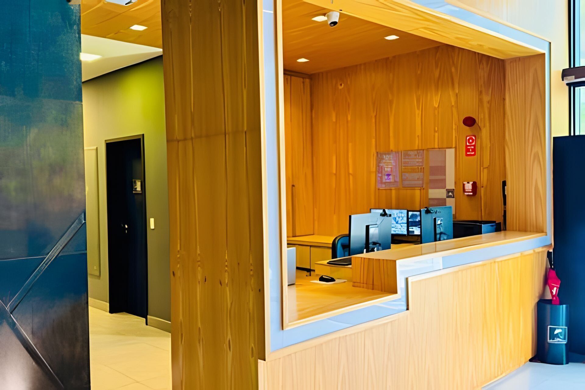 Een receptiegedeelte met een houten bureau, computermonitoren en een brandblusser.